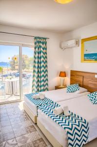 two beds in a bedroom with a view of the ocean at Tommy's Rooms in Haraki