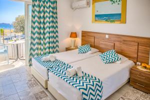 two beds in a bedroom with a view of the ocean at Tommy's Rooms in Haraki