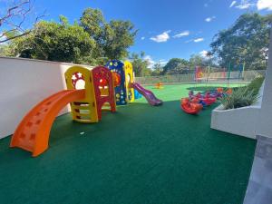 a childrens playground with a play equipment on the grass at Flat Park Veredas com Vista Serra com geladeira e fogão in Rio Quente