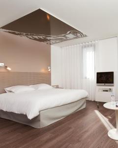 a bedroom with a white bed and white walls at ibis Styles Lille Aéroport in Lesquin