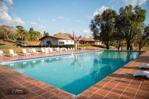 a large swimming pool with chairs and a house at Pousada Recanto do Turvo in Capitólio