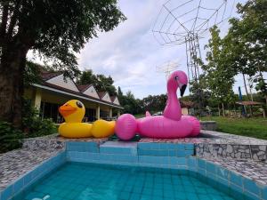 3 canards gonflables assis à côté d'une piscine dans l'établissement Phutawan Resort, à Chai Badan