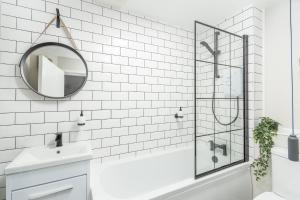 a white bathroom with a tub and a mirror at NEWLY RENOVATED, Chestnut Court, 2-Bedroom Apts, Private Parking, Fast Wi-Fi in Leamington Spa