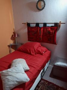 a bedroom with a bed with red sheets and pillows at La Casita in Neuquén