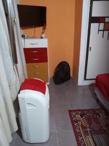 een woonkamer met een tv en een witte kruk bij La Casita in Neuquén