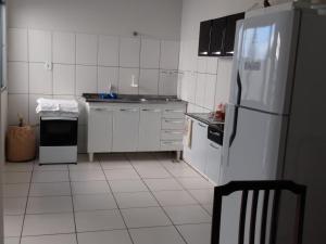 a kitchen with white appliances and a white tiled floor at Casa São José da Barra Capitólio in Elisiário Lemos