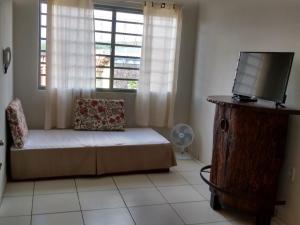- un salon avec un canapé, une télévision et une fenêtre dans l'établissement Casa São José da Barra Capitólio, à Elisiário Lemos
