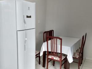 a kitchen with a table and a white refrigerator at Casa São José da Barra Capitólio in Elisiário Lemos