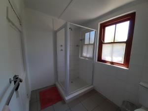a white bathroom with a shower and a window at The Owlhouse Backpackers in Nieu-Bethesda
