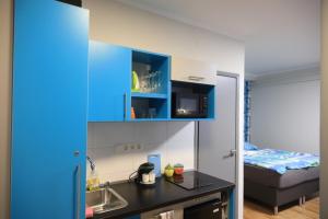 a small kitchen with blue cabinets and a bed at Studio Gold apartman in Pécs