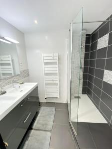 een badkamer met een glazen douche en een wastafel bij Charmant T3 cosy À 2 pas du bourg et des plages in Larmor-Plage