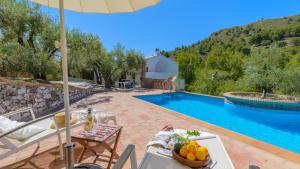 eine Villa mit einem Pool mit einem Tisch und Stühlen in der Unterkunft Finca Colores en el Viento Frigiliana by Ruralidays in Frigiliana