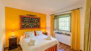ein Schlafzimmer mit einem Bett mit gelben Wänden und einem Fenster in der Unterkunft Finca Colores en el Viento Frigiliana by Ruralidays in Frigiliana