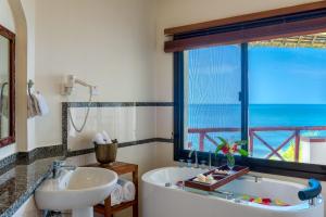 a bathroom with a tub and a sink and a window at Sea Cliff Resort & Spa in Zanzibar City
