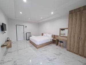een slaapkamer met een bed, een bureau en een televisie bij Nub Thong Residence in Kalasin