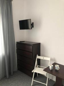 Cette chambre comprend une chaise, une commode et une télévision. dans l'établissement Noclegi Jachtklub Elbląg, à Elbląg