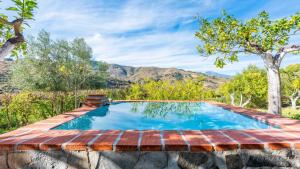 an outdoor pool with a red brick retaining wall and trees at Casa Ami Guaro by Ruralidays in Guaro