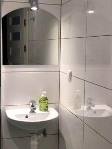La salle de bains blanche est pourvue d'un lavabo et d'un miroir. dans l'établissement Noclegi Jachtklub Elbląg, à Elbląg