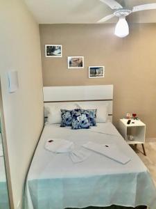 a bedroom with a white bed with blue pillows at Pontal Praia Suítes in Arraial do Cabo