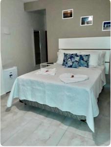 uma grande cama branca com um edredão azul em Pontal Praia Suítes em Arraial do Cabo