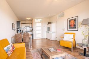 ein Wohnzimmer mit gelben Stühlen und einem Tisch in der Unterkunft Appartementencomplex Juliana 154 in De Koog