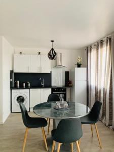 a kitchen with a glass table and chairs in a room at St Louis Appartement in Roanne