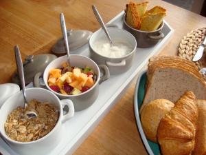 a tray of food with bowls of food and bread at B&B De Grote Plaats in Hoogstraten