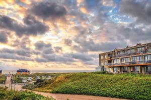 a building on top of a hill next to the ocean at Appartementencomplex Juliana 176 in De Koog