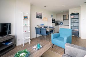 a living room with a blue chair and a table at Appartementencomplex Juliana 176 in De Koog