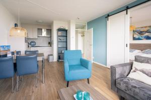 a living room with a blue chair and a couch at Appartementencomplex Juliana 176 in De Koog +2 photos