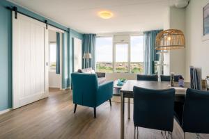 a dining room with a table and blue chairs at Appartementencomplex Juliana 176 in De Koog