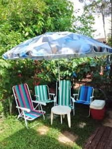 3 chaises et un parasol dans la cour dans l'établissement Kitconforto, à Guarujá