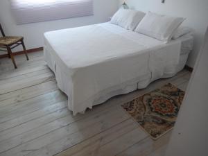 a bedroom with a bed with white sheets and a rug at GARDENIA in Balneario Buenos Aires