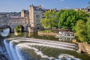 a boat in a river in front of a bridge at Stunning, 1 Bed Luxury Flat in Central Bath in Bath