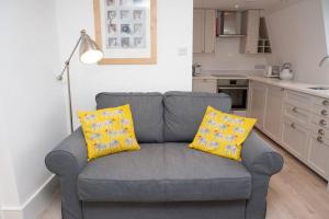 a grey couch with yellow pillows in a kitchen at Spectacular views, 1 Bed Central Bath Apartment in Bath