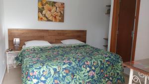 1 dormitorio con 1 cama con una manta colorida en Pousada Villa Virgínia Guarujá, en Guarujá