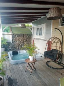 uma banheira de hidromassagem num pátio com uma cadeira em Appartement d'une chambre avec vue sur la ville jacuzzi et jardin clos a Le Vauclin a 2 km de la plage em Le Vauclin