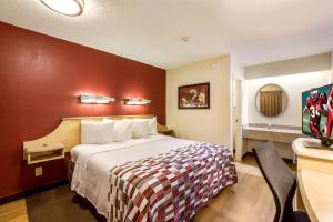 a hotel room with a bed with a red wall at Red Roof Inn Detroit - Plymouth/Canton in Plymouth