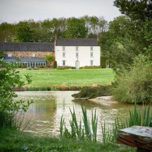 ein weißes Haus mit einem Teich davor in der Unterkunft Heron House at Millfields Farm Cottages in Hognaston