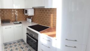 uma cozinha com armários brancos e uma parede de tijolos em WHome Modern 1-Bed with AC & private Terrace em Lisboa