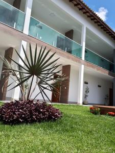 a large white building with a palm tree in the yard at Pousada e Casas João e Ana in Barra Grande