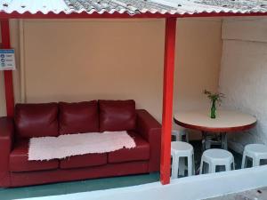 un sofá rojo, una mesa, una mesa y un taburete en Portal Amor e Luz Hospedagem, en São Thomé das Letras