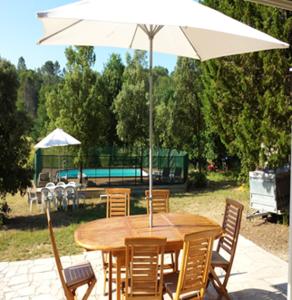 Flassans-sur-IssoleにあるVilla de 3 chambres avec piscine privee jardin amenage et wifi a Flassans sur Issoleの木製テーブルと椅子(傘付)