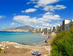 马尔萨拉Cozy apartment in Marsala 27 m² with garden balcony的海岸边的海滩上有一个蓝色的船