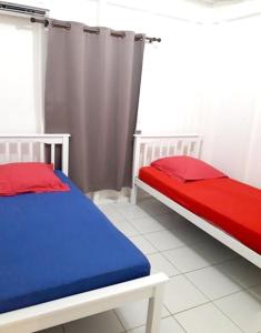 a bedroom with two beds with red and blue sheets at Maison cosy Le Lamentin, jardin in Le Lamentin