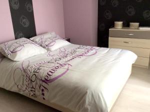 a bedroom with a bed with purple and white sheets and pillows at Maison de 4 chambres avec jardin clos et wifi a Tregomeur a 8 km de la plage in Trégomeur