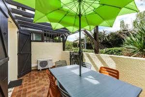 uma mesa com um guarda-chuva verde num pátio em Maison de 2 chambres a Saint Cyprien Plage a 300 m de la plage avec jardin amenage et wifi em Saint-Cyprien