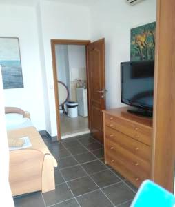 uma sala de estar com televisão numa cómoda de madeira em 2 bedrooms apartement with sea view enclosed garden and wifi at Ulcinj 1 km away from the beach em Ulcinj