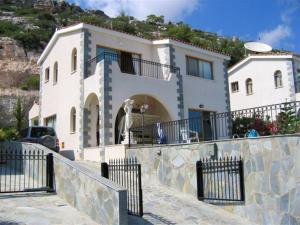 una gran casa blanca con una valla delante en Peyia Villa with sea view, private pool, and garden, en Peyia