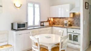 eine weiße Küche mit einem weißen Tisch und Stühlen in der Unterkunft Maison de 2 chambres a Le Bois Plage en Re a 400 m de la plage avec piscine partagee terrasse amenagee et wifi in Le Bois-Plage-en-Ré